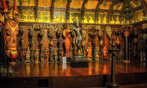 A museum interior with a central statue, wooden panels, and various cultural artifacts. - Collection O Kadavanthra (Kanayannur)