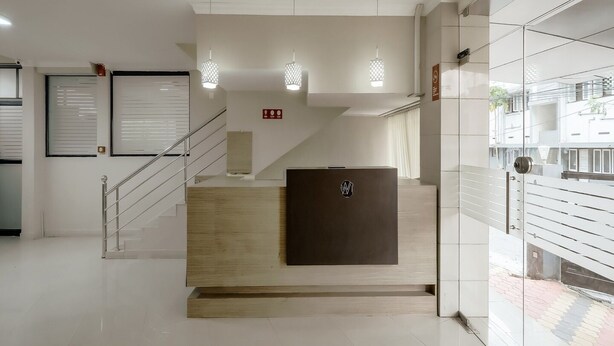A modern reception area with a wooden reception desk, a staircase, and pendant lighting.