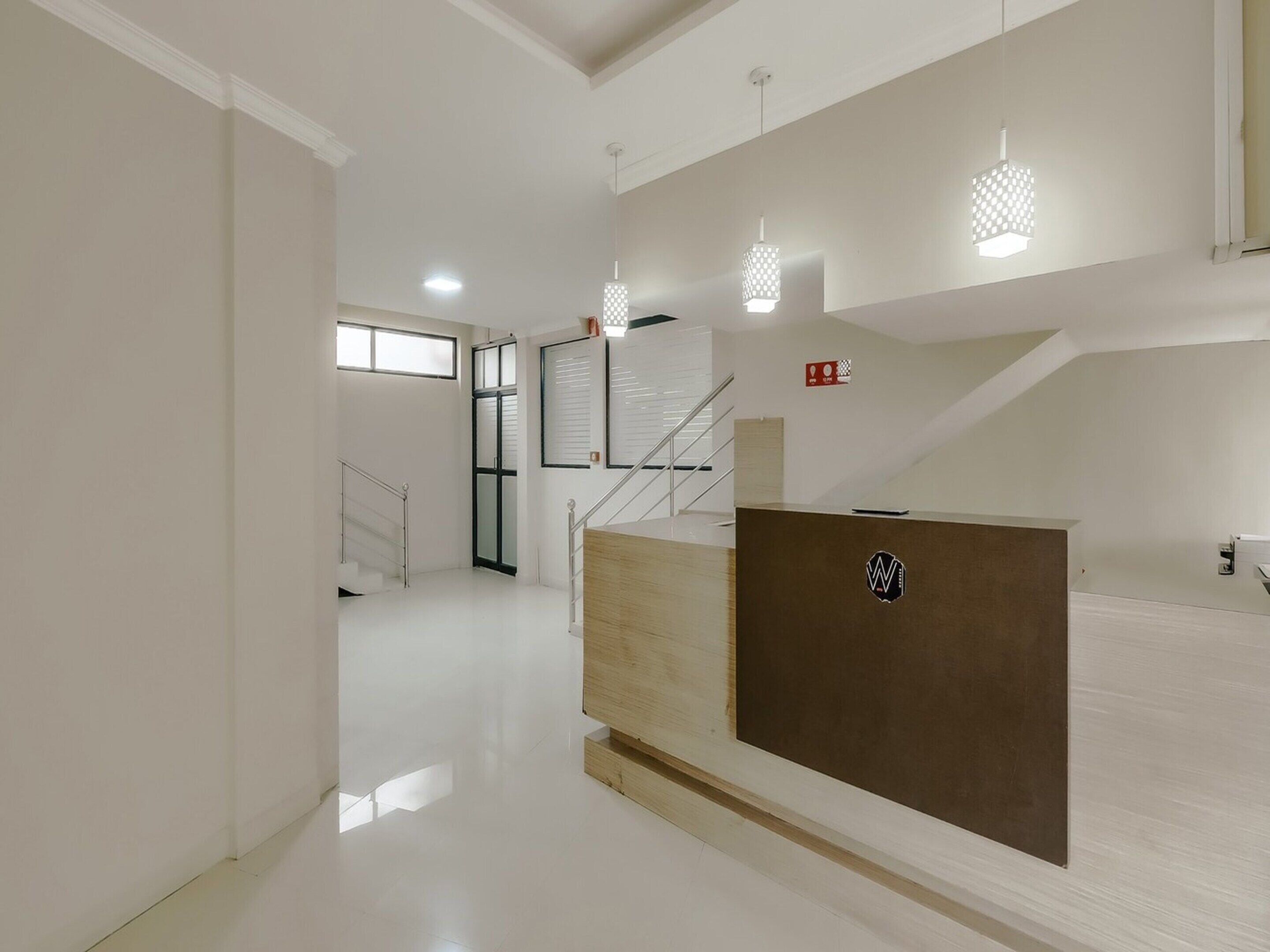 A modern interior with a reception desk, a staircase, and pendant lighting.