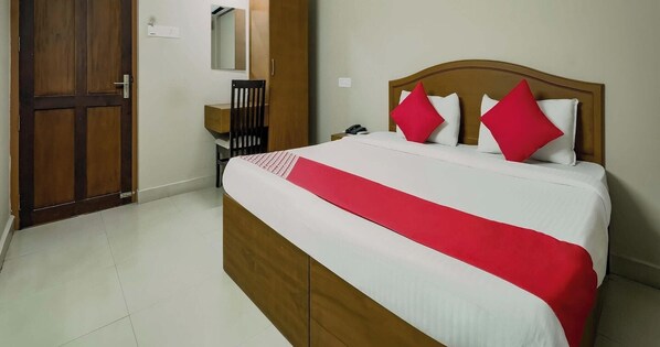 A hotel room with a wooden bed, a desk, a chair, and a wardrobe. - Collection O Kadavanthra (Kanayannur)