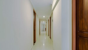 A long, narrow hallway with white walls and wooden doors.