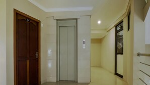A hallway with a wooden door, an elevator, and a glass door with a metal handle.