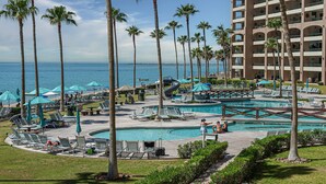 A resort with multiple pools, palm trees, and a view of the ocean. - Beautiful Beachfront Retreat With Panoramic Ocean Views (Backus)