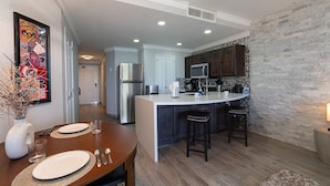 A modern kitchen with a central island, dark wooden cabinets, a stainless steel refrigerator, and a microwave. - Stunning Oceanfront Escape With Sweeping Sea Views (Puerto Peñasco)