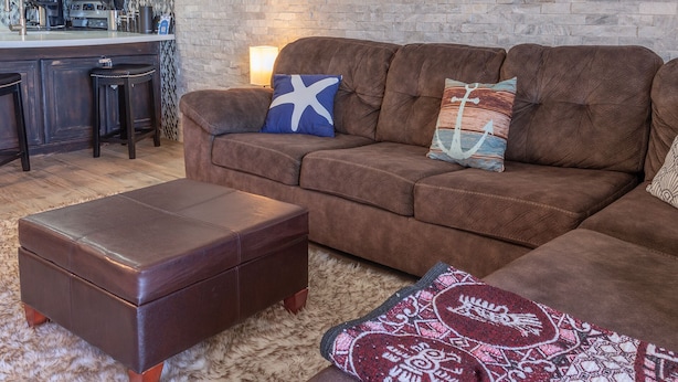 A brown leather sofa with two decorative pillows, a matching ottoman, and a patterned throw on a furry rug. - Stunning Oceanfront Escape With Sweeping Sea Views (Puerto Peñasco)