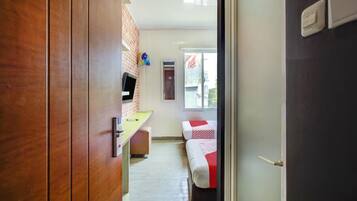 A corridor leading to a room with a bed, a desk, and a television.