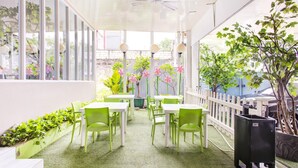 An indoor patio area with tables and chairs, a white fence, and potted plants. - Stylish Twin Suite Escape W/ Free Wifi and Parking (Jakarta)