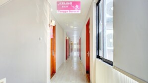 A hallway with a sign indicating an exit, a radiator, and a window. - Stylish Twin Suite Escape W/ Free Wifi and Parking (Jakarta)