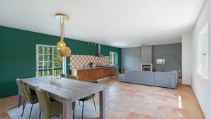 Eine moderne Küche mit kariertem Fliesenspiegel, ein Essbereich mit Holztisch und -stühlen sowie ein graues Sofa im Wohnbereich.
