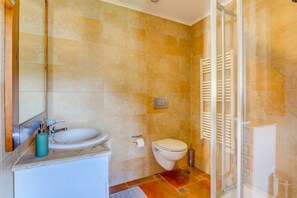 A bathroom with a sink, toilet, and shower area.