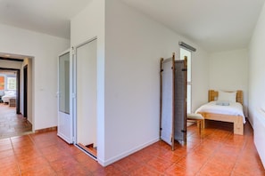 A bedroom with a bed, a wardrobe, and a door leading to another room.