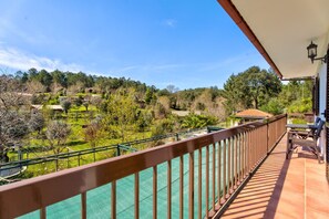 A balcony with a view of a green landscape and trees.