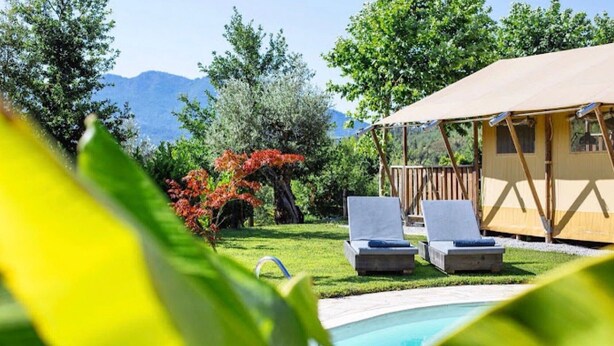 Ein Pool mit zwei Liegestühlen, einem überdachten Bereich und einer Bergkulisse.