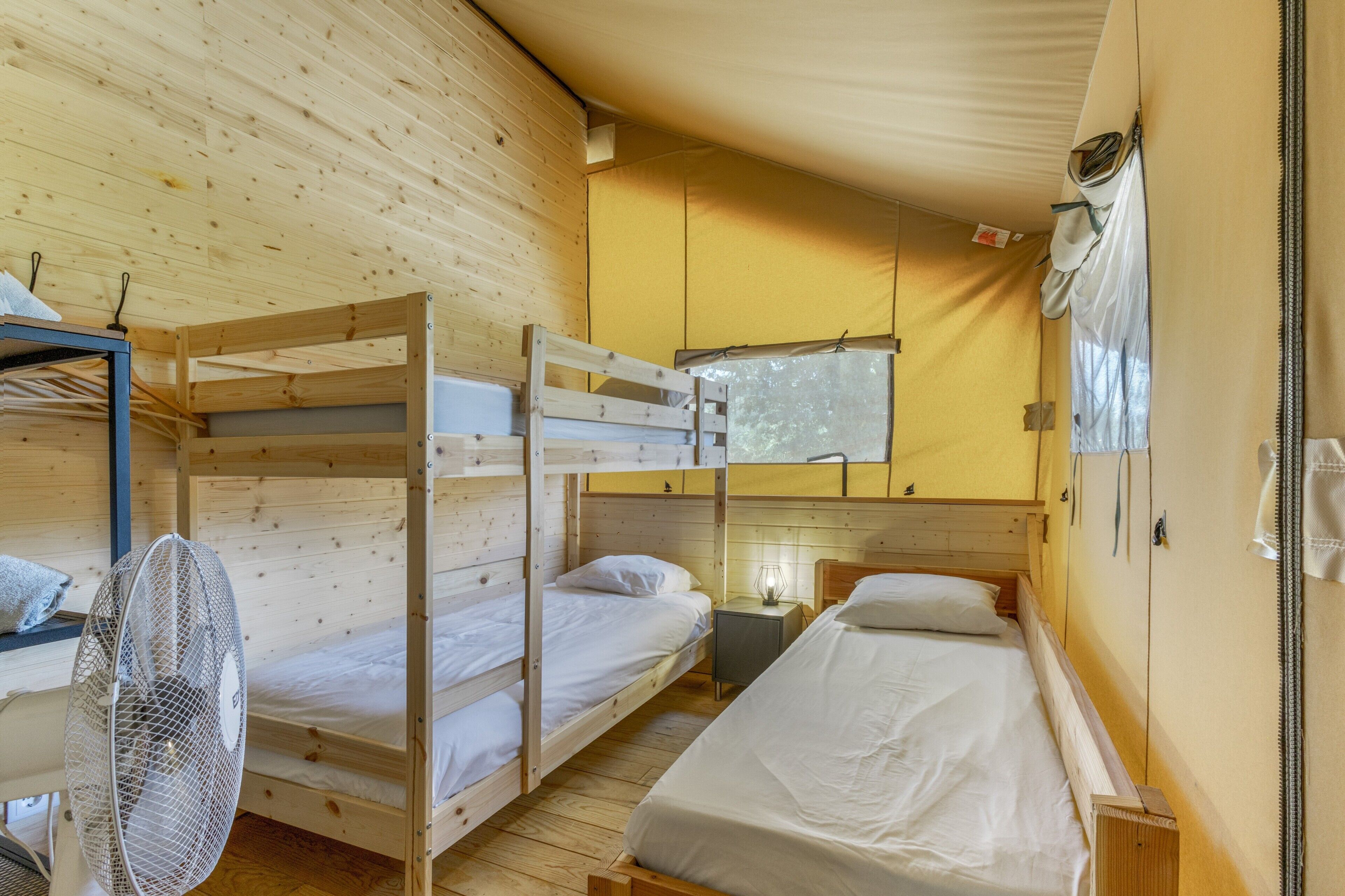 A room with bunk beds, a fan, and a window.