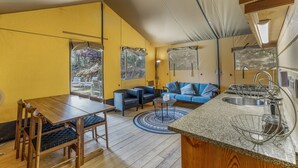 A compact living space with a dining area, a sofa, and a kitchenette. - Boavista Glamping Tent with Mountain View, Private Pool and Wi-Fi (Arco de Baúlhe)