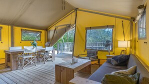 A room with a wooden floor, a sofa, a table, chairs, a fan, and windows. - "Pinheiro Glamping" Tent with Mountain View, Private Pool and Wi-Fi (Arco de Baúlhe)