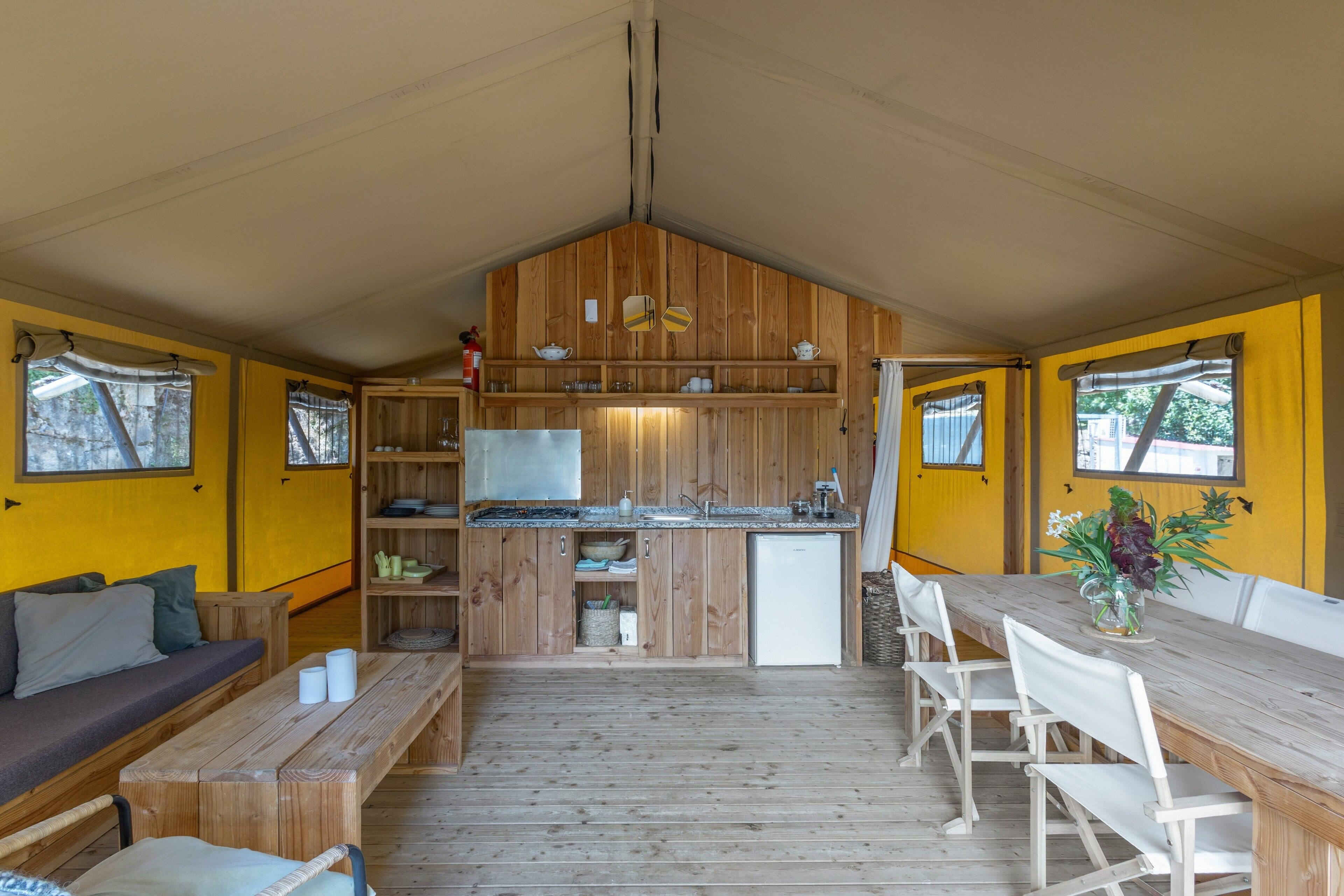 A compact kitchen with wooden cabinets, a sink, and a dining area with a long table and chairs.