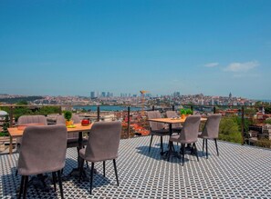 Een terras met stadszicht, tafels, stoelen en een vloer met een patroon.
