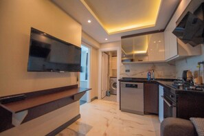 Una cocina moderna con lavavajillas integrado, un televisor de pantalla plana en la pared y una pequeña isla con pileta.