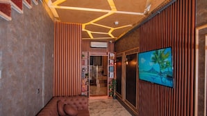 A modern interior with a sectional sofa, a television mounted on the wall, and a patterned ceiling. - Mar boutique's luxury apartment (FATIH)