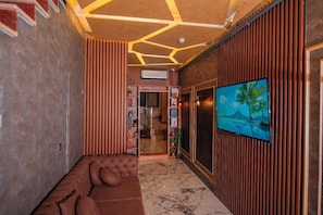 Ein modernes Interieur mit einer Eckcouch, einem an der Wand montierten Fernseher und einer strukturierten Decke.