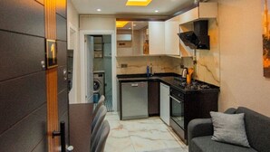A modern kitchen with a built-in stove, a dining area with a table and chairs, and a living area with a sofa. - Mar boutique's luxury apartment (FATIH)
