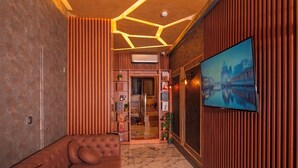 A modern interior with a brown leather sofa, a marble floor, wooden paneling, and a large TV screen displaying a cityscape. - Mar boutique's luxury apartment (FATIH)