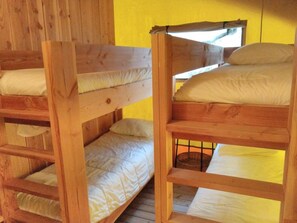 Des lits superposĂ©s avec des structures en bois et du linge de lit blanc, une fenĂȘtre avec vue et un mur jaune.