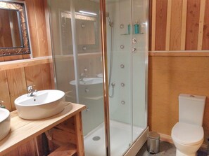 Une salle de bain avec une douche Ă parois de verre, un lavabo blanc et des toilettes.