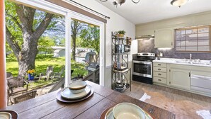 A kitchen with a large window, a chandelier, and a dining area with a table set for two. - Santa Fe 1976! Work Travel Stay Awhile Game Room! (Ottawa)