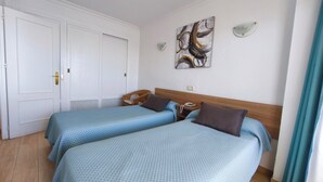 Ein Hotelzimmer mit zwei Betten, einem Holzkopfteil, einem Wandbild und einer weißen Tür.