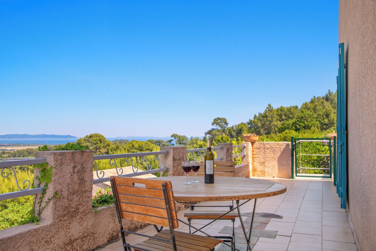 A terrace with a table and chairs, a bottle of wine, and a view of the landscape.