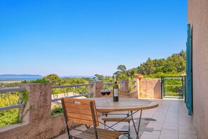 Eine Terrasse mit Tisch und Stühlen, einer Weinflasche und Blick auf die Landschaft.