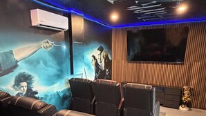 Une salle de cinéma privée dotée d’un grand écran, de sièges confortables et d’une fresque murale.