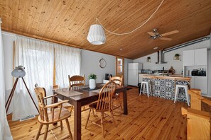 A wooden interior with a dining area, kitchen, and ceiling fan.