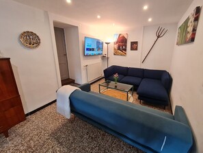 Un salon avec un canapé, une table basse, un téléviseur et un tableau accroché au mur.