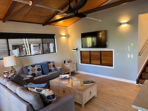 A living room with a sofa, coffee table, and a TV mounted on the wall.
