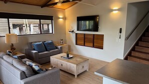 Un salon moderne avec un canapé, une table basse et un téléviseur.