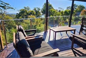 Eine Terrasse mit Holzmöbeln, darunter Stühle und ein Tisch, mit Blick auf eine bewaldete Landschaft.