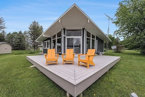 Ein Haus mit Terrasse, drei Stühlen und einer Satellitenschüssel.