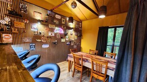 Un coin repas avec une table et des chaises en bois, un mur en bois orné de différents panneaux, et une fenêtre avec des rideaux.