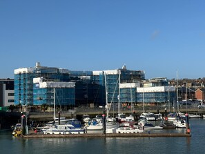 Un porto turistico con imbarcazioni ormeggiate, un edificio in costruzione con impalcature e un cielo azzurro intenso.
