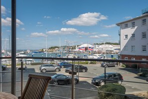 A marina with boats, a British flag, and a building with a red and white facade. - Marina View  Stylish 2 Bed Waterfront in Cowes (Cowes)