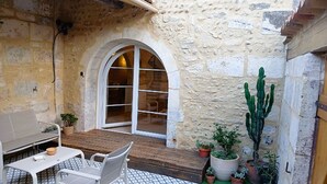 A stone-walled patio with a wooden table and chairs, a white sofa, and a large cactus plant. - Mas de l'Amarine Between Camargue and Provence (Bellegarde)