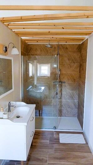 A bathroom with a shower, sink, and mirror.