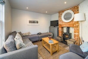 A cozy living room with a sofa, a coffee table, a fireplace, and a television. - Abaca House with 3 bedrooms and 2.5 bathrooms (Cowes)