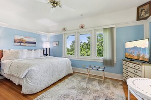 Un dormitorio con una cama, televisión, ventana con vistas y ventilador de techo.