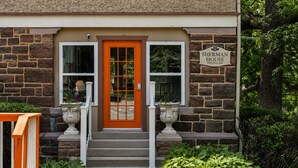 Un edificio de piedra con puerta roja, dos ventanas y un cartel que dice 'Sherman House White Rose Inns'.