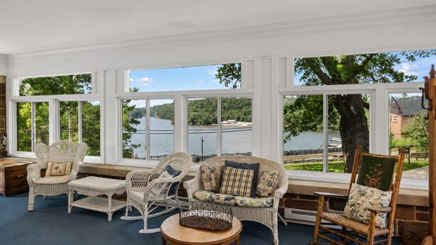 Una habitación con ventanas amplias, muebles de mimbre y vistas a un lago.