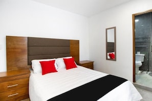 A hotel room with a bed, a wooden headboard, a nightstand, a mirror, and a view of the bathroom. - HOTEL SAN JOSE CENTRO HISTORICO (San Luis Potosí)